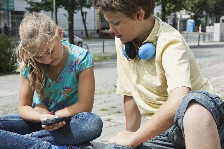 Germany Berlin Boy and girl sitting with cell phone and headphone