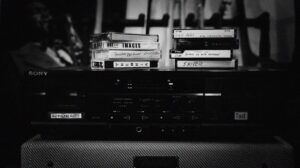 Black-and-white image of a Sony stereo with cassette tapes stacked on top.