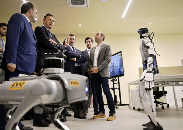 Group of suited professionals observing a humanoid robot and a robotic dog in a modern lab during a demonstration.
