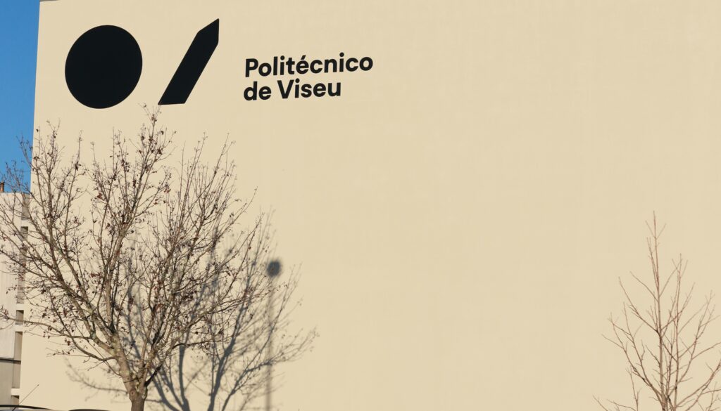 Beige exterior wall displaying the sign 'Politécnico de Viseu' with bare tree branches in front. Instituto Politécnico de Viseu promove sessão sobre tecnologias emergentes aplicadas à indústria