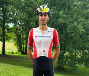 Portuguese cyclist in national team kit standing outdoors in a park with a helmet and sunglasses on his head