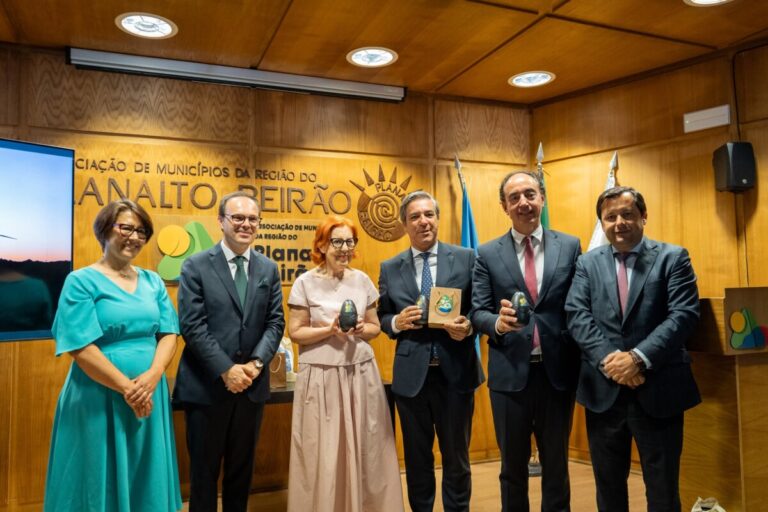 Group of six professionals in formal attire posing with awards in a wood-paneled conference room.