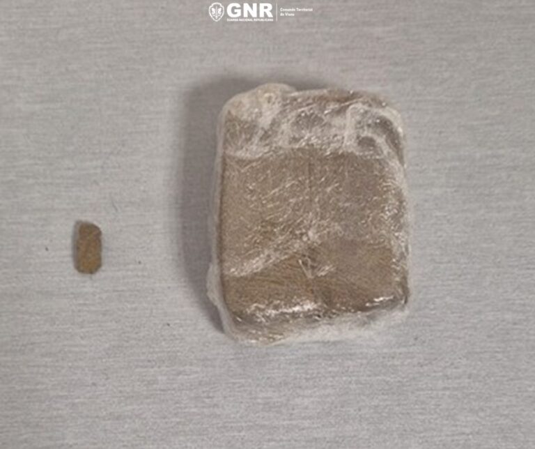 Brown rectangular block wrapped in plastic on a light surface, with a small piece to its left.