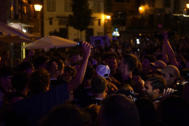 A crowded nighttime street party with people close together and hands raised in the air. Académico de Viseu com plantel “coeso e humilde” no regresso à I Liga, 37 anos depois
