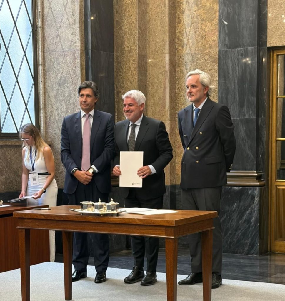 Three men in suits stand behind a wooden table in a marble-walled room, one holding a document; a woman adjusts papers to the left. Antigo edifício do SLAT passa para a posse da Câmara de Viseu