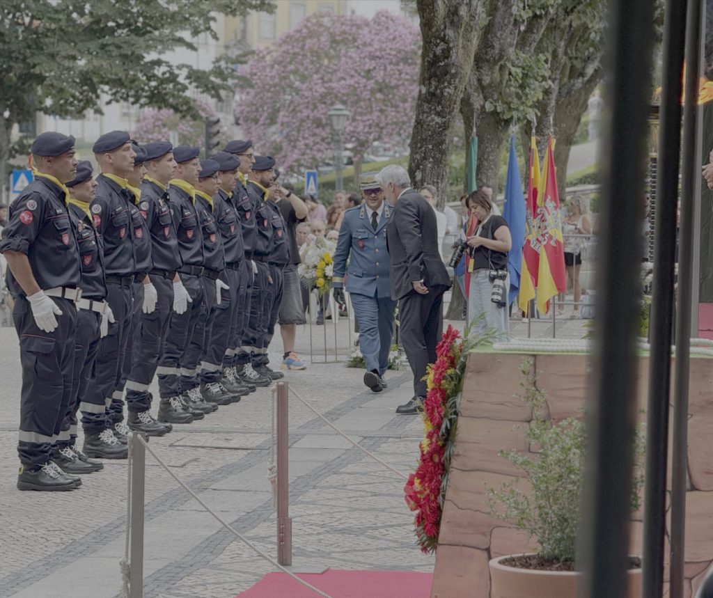 Line of uniformed guards in black outfits with yellow scarves standing in a row as officials walk by during a ceremony. Sapadores de Viseu assinalam 199 anos com entrada da primeira mulher no corpo de bombeiros
