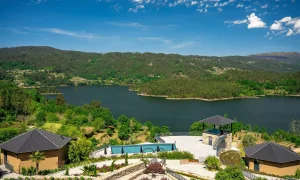 Sunny lakeside resort with a large body of water, green hills, and pavilion structures in the foreground