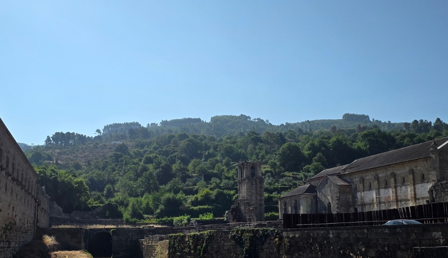 Ruined stone buildings along a hillside with a small bell tower and clear blue sky behind them Autarquia de Tarouca aguarda limpeza do horto do Mosteiro após concluir intervenção no ribeiro