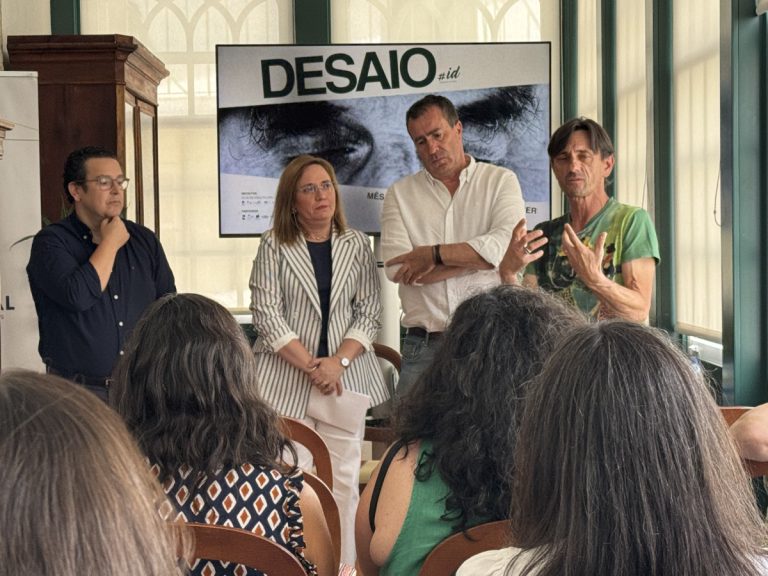 Panel of four people speaking to an audience, with a large 'DESAIO' banner behind them and an eye image on the screen behind.