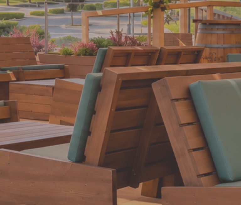 Stacked wooden outdoor benches and chairs with blue cushions in a sunny patio setting