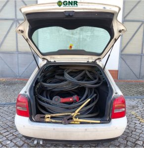 Open white car trunk filled with coiled hoses and cables, plus clamps and a red tool; GNR logo on the lid.