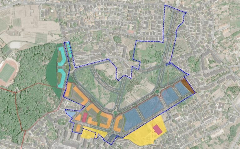 Aerial map of a planned area showing a blue dashed boundary outlining a large park and surrounding development with color‑coded zones in yellow, orange, blue, and brown. Roads and residential blocks are visible inside and around the boundary.