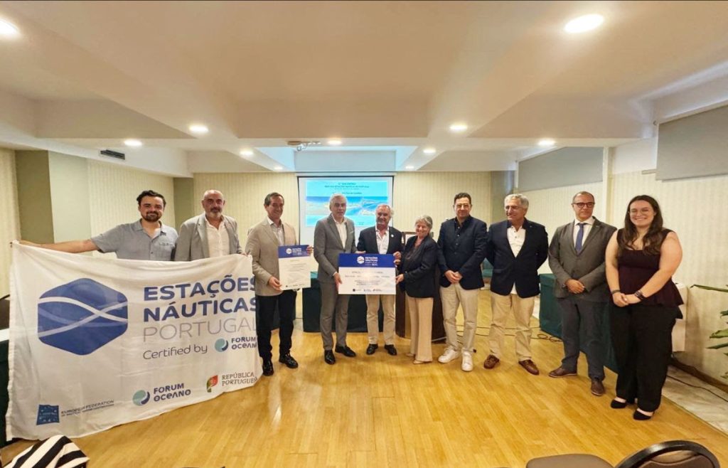 Group of ten people in a conference room posing with two large certificates; banner on the left reads Estações Náuticas Portugal and logos in the foreground.