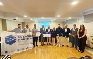 Group of ten people in a conference room posing with two large certificates; banner on the left reads Estações Náuticas Portugal and logos in the foreground.