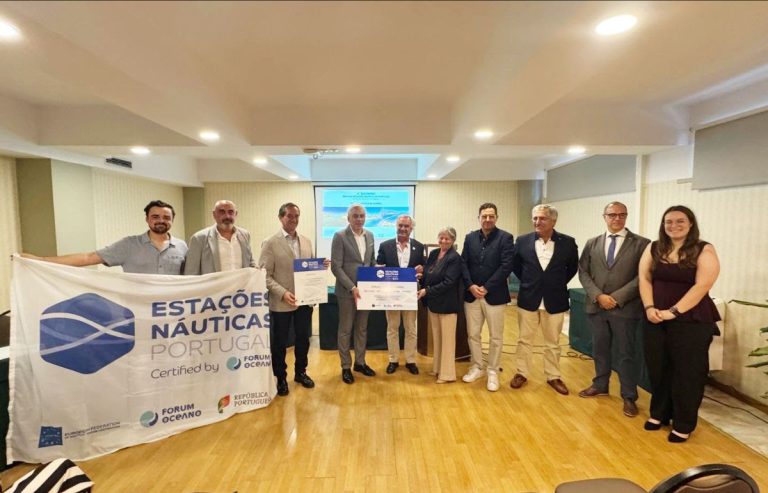 Group of ten people in a conference room posing with two large certificates; banner on the left reads Estações Náuticas Portugal and logos in the foreground.